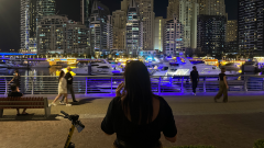 A person on the phone looking into the Dubai night skyline.