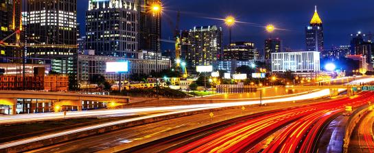 Light trails from car traffic on a highway in front of the midtown Atlanta skyline